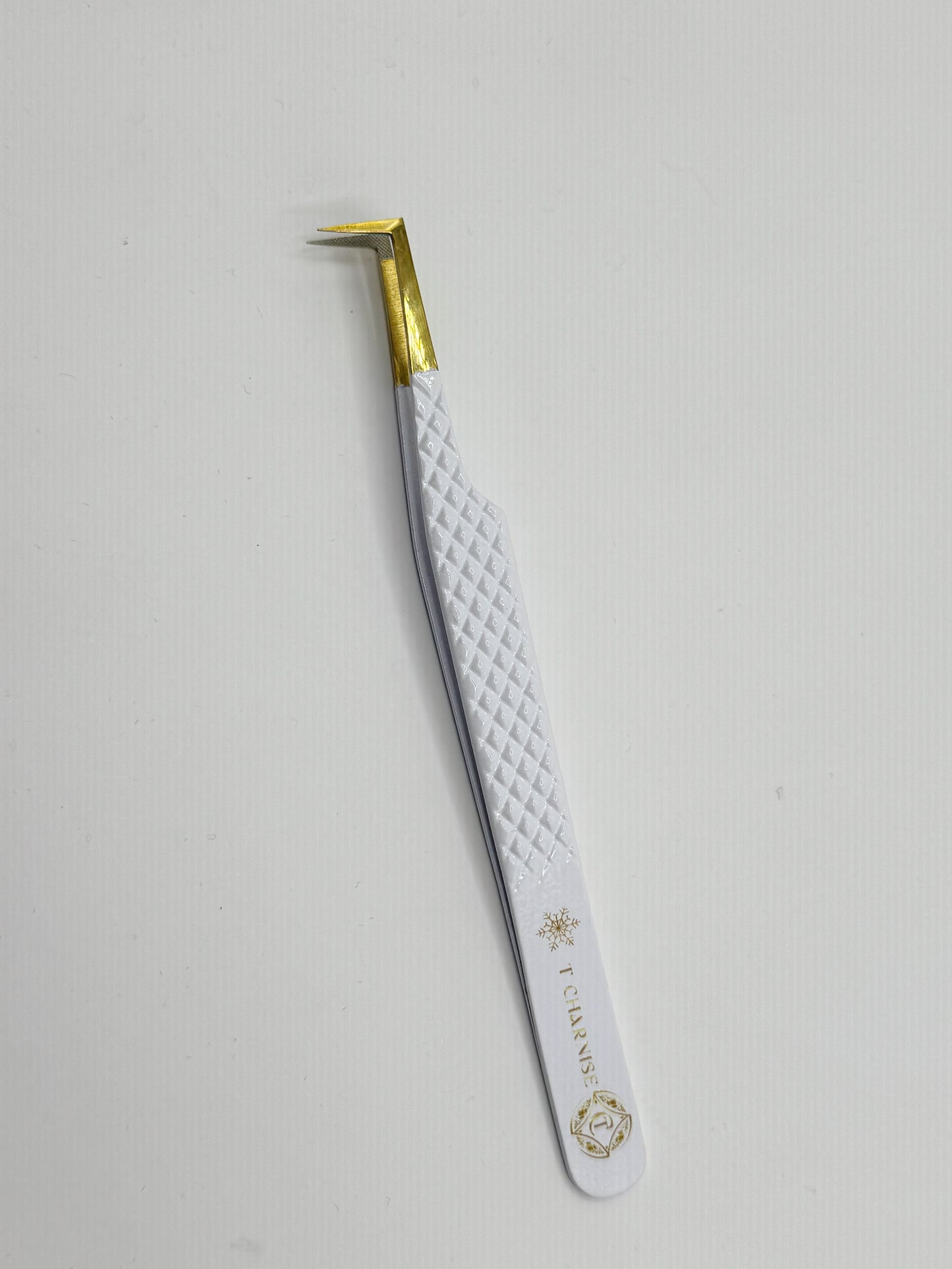 Eyebrow tweezer with white handle and gold accents on a light gray background